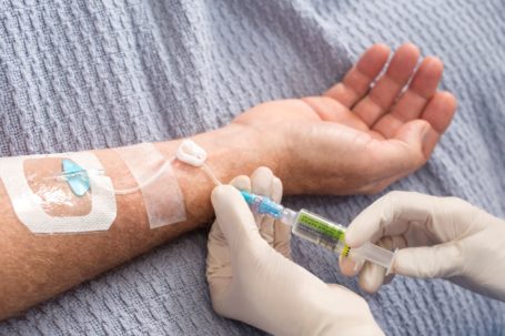 A healthcare worker maintains a peripheral vascular access device on a patient.